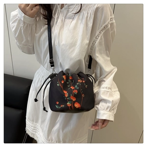 Detail view of a black drawstring bucket bag featuring red persimmon oriental patterns