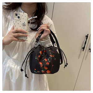 Détail du sac seau noir à cordon avec imprimé kaki et broderies dorées élégantes