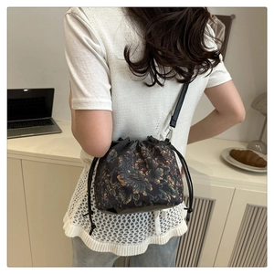 Détail du sac seau vintage avec motifs de pivoines dorées sur fond noir élégant