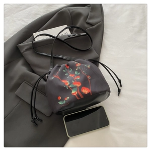 Détail du sac à cordon noir avec motif de persimmon rouge à côté d'un smartphone