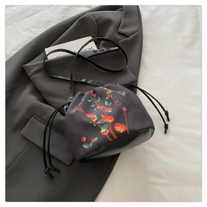 Détail d'un sac seau à cordon avec base en cuir et imprimé de kakis éclatants