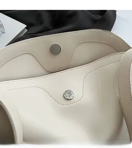 Close-up of magnetic silver buckles and fine stitching on a beige tote bag