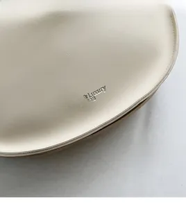 Detail of creamy white leather tote with silver embossed logo and lychee texture