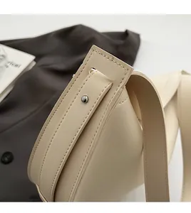 Close-up of handmade stitching and silver rivet on an off-white leather tote bag