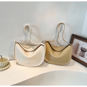Minimalist half-moon hobo bags in beige and khaki leather displayed on a white stand