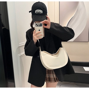 Chic cream-white crescent shoulder bag styled with a modern casual outfit and blazer