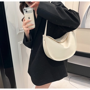Detail of off-white crescent tote bag showing smooth leather texture and elegant drape