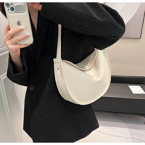 Model selfie showcasing a stylish creamy white crescent shoulder bag in vegan leather