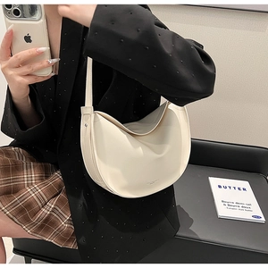Detail of a minimalist cream white half-moon shoulder bag with fine leather texture
