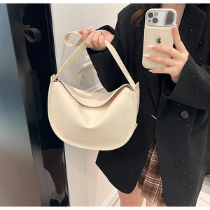 Close-up of beige moon-shaped hobo bag featuring elegant pleated layers and glossy leather finish