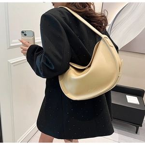 Close-up of a cream crescent hobo bag with adjustable side strap and luxury logo detail