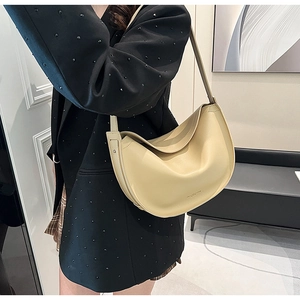 Detail of a creamy beige half-moon tote bag in smooth leather with gold logo