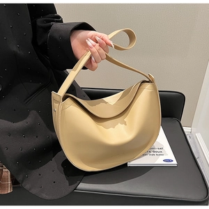 Detail of a beige crescent-shaped leather bag with fine texture and subtle logo embossing