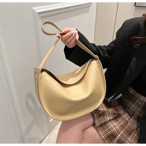 Detailed view of cream leather half-moon tote bag worn by model on shoulder