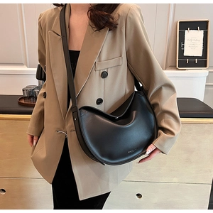 Detail shot of black leather hobo bag with adjustable wide strap on khaki blazer