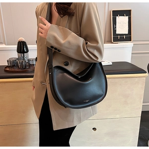 Detail of minimalist black leather crescent bag showing fine stitching and matte texture