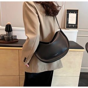 Detail of minimalist black leather crescent hobo bag with printed brand logo on surface