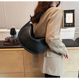 Detail view of the sleek black crescent hobo bag featuring silver logo and wide strap