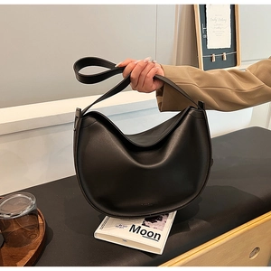 Detailed view of a black minimalist crescent tote bag with a wide adjustable shoulder strap