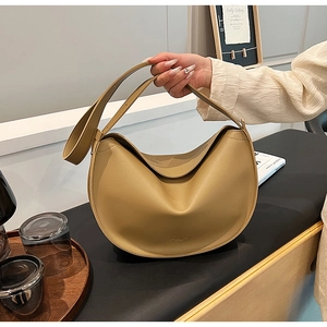 Detail of khaki leather hobo bag featuring wide strap and minimalist brand embossing