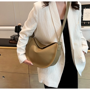 Detail of khaki crescent crossbody bag with wide shoulder strap in casual setting