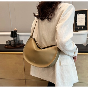 Khaki hobo shoulder bag shown on model in a cozy interior setting with soft lighting