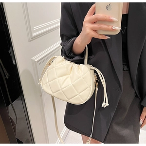 Close-up of quilted cream bucket bag with drawstring closure and fine leather handle