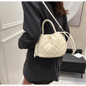 Close-up of beige quilted leather bucket bag featuring drawstring details and crossbody strap