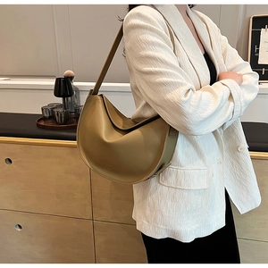 Detail of an olive green crescent tote bag styled with a textured white blazer