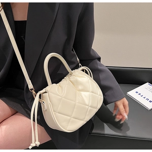Close-up of cream quilted PU leather handbag with drawstring top and crossbody strap