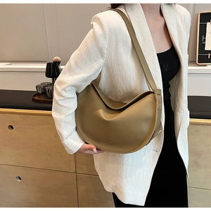 Detail of minimalist khaki crescent bag made of matte leather worn over the shoulder