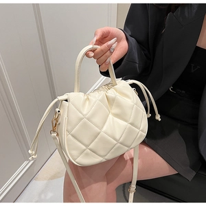 Detail of quilted leather texture and adjustable strap on cream bucket bag