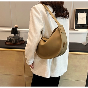 Close-up of khaki leather crescent bag with gold logo detail and smooth matte finish
