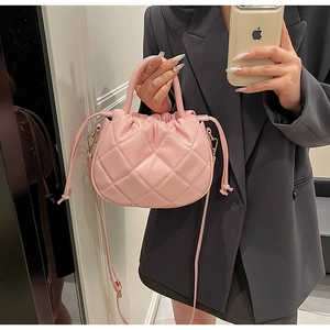 Detail of light pink quilted bucket bag with drawstring closure and soft texture