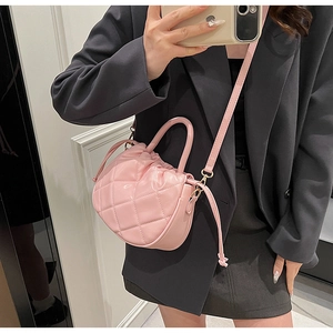 Close-up of light pink quilted bucket bag with drawstring and adjustable strap