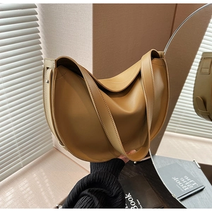 Close-up of a warm camel leather hobo bag with adjustable strap in natural sunlight