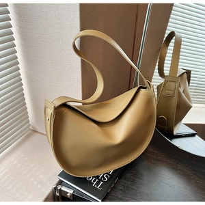Detail of light brown crescent tote bag featuring pleated faux leather and metal rivets