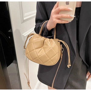 Quilted beige bucket bag featuring a drawstring closure and a soft leather-like finish
