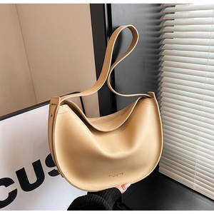 Detail of a beige half-moon hobo bag in matte leather showing the modern curved shape and strap