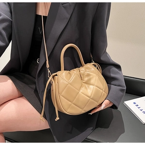 Close-up of khaki quilted bucket bag featuring drawstring closure and top handle detail