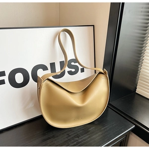 Detail of minimalist camel leather crescent bag with smooth matte finish and wide strap