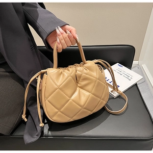 Detail of quilted leather handbag with drawstring closure and twin circular handles