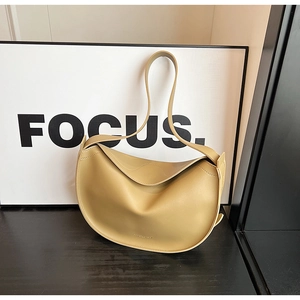 Detailed close-up of a beige crescent tote bag with fine stitching and matte leather finish
