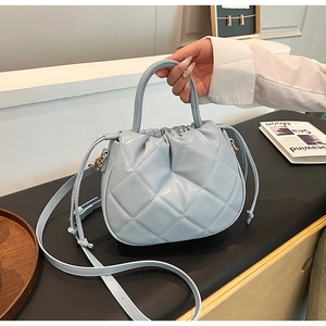 Macro shot of light blue quilted leather bucket bag with drawstring and top handle