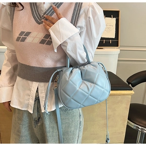 Detail of light blue quilted bucket bag with a soft faux leather texture and top handle