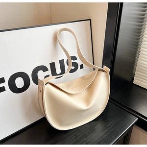 Detail view of a minimalist cream crescent tote bag on a marble surface with natural light