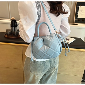 Detail of light blue quilted drawstring bucket bag with textured diamond pattern