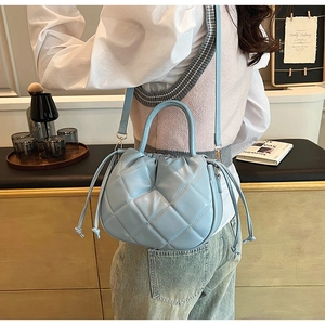 Macro shot of sky blue quilted bucket bag showing leather texture and drawstring detail