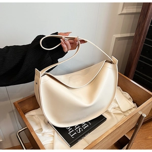 Close-up detail of smooth cream white hobo bag showing the subtle embossed logo and texture