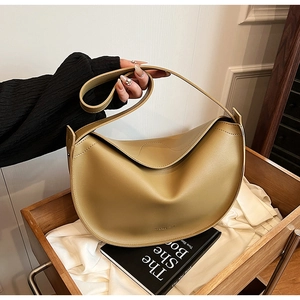 Detail of matte khaki crescent tote bag with premium leather texture on a wooden cart